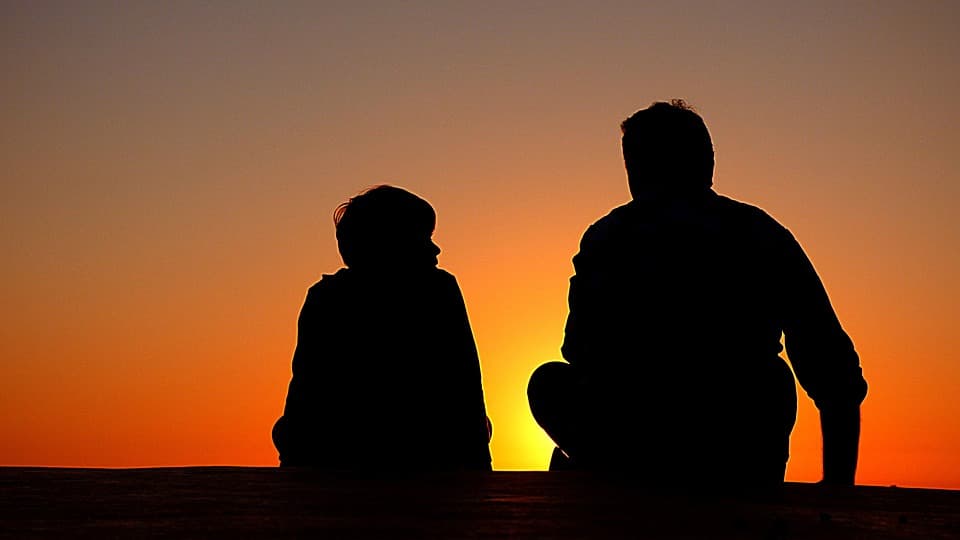 Pai e filho conversando no pôr do sol.