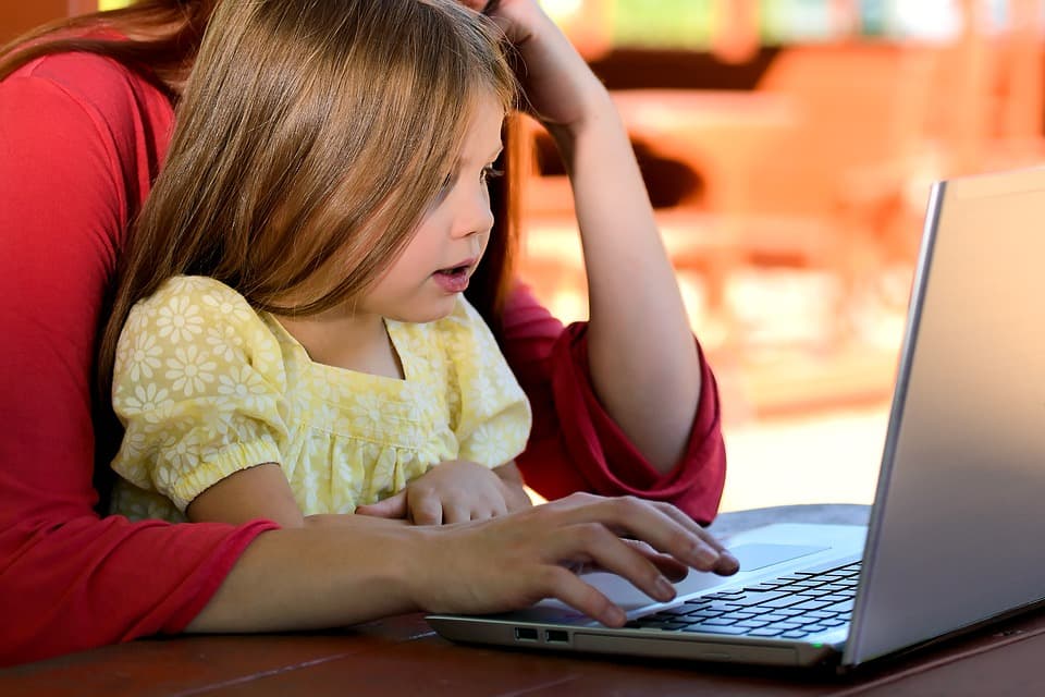 Criança usando um computador com a mãe.